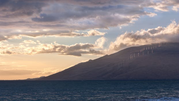 Serene sunset view over Kihei, Hawaii with wind turbines along the coast, capturing nature and renewable energy.
