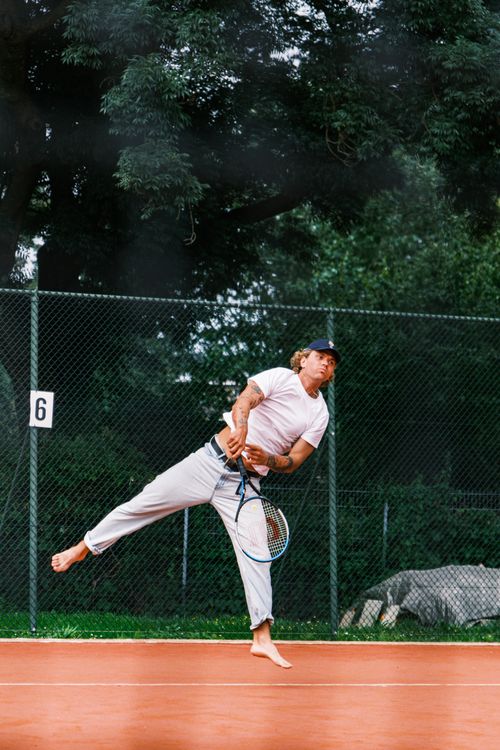 Free Barefoot tennis player serving on outdoor court, showcasing dynamic motion and energy. Stock Photo