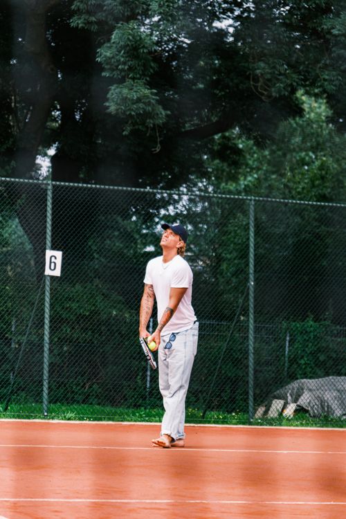 Free A relaxed tennis player on a clay court, barefoot and ready to serve. Stock Photo