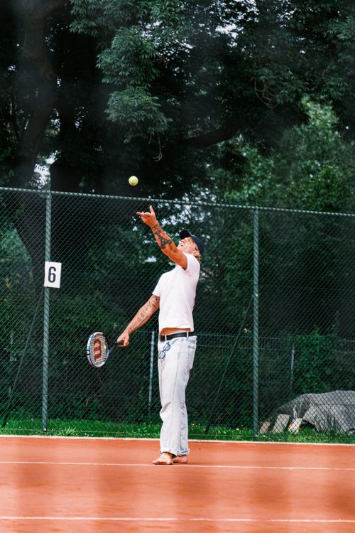 Free An adult man serves during a tennis match on an outdoor clay court. Stock Photo