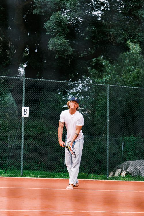 Free Adult male tennis player in action on outdoor clay court, focusing on serve. Stock Photo