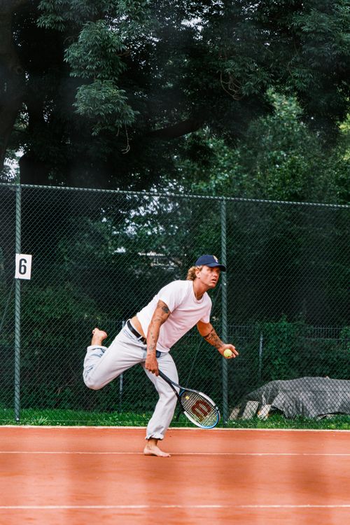 Free Young male tennis player serving on an outdoor clay court, showcasing athletic form and focus. Stock Photo
