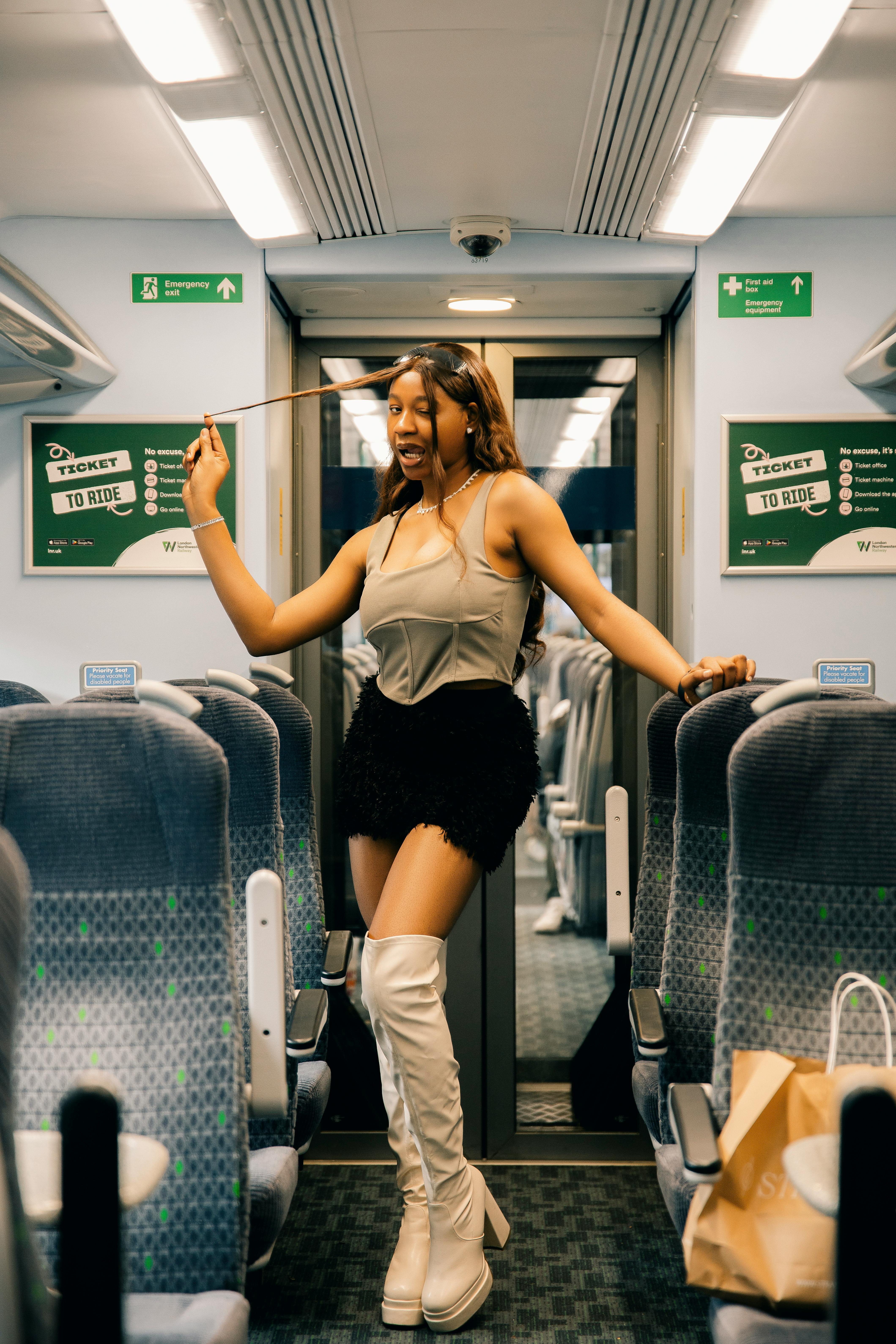 Free Confident woman posing stylishly inside a modern train cabin, embracing fashion and travel vibes. Stock Photo