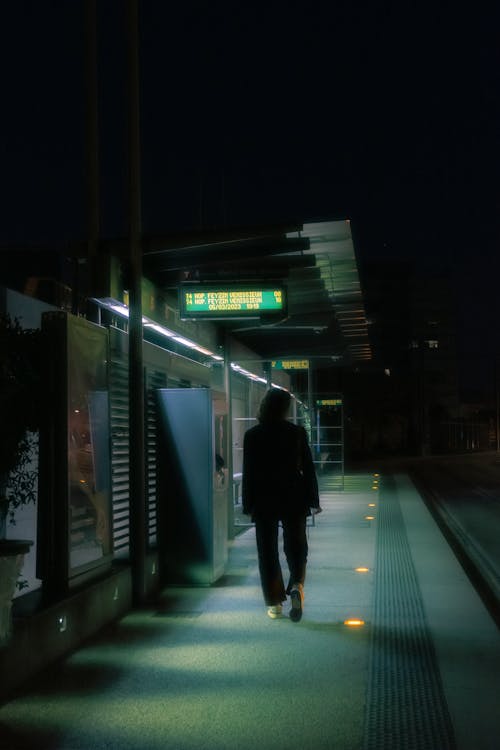 A Person Walking on the Platform at the Station at Night 