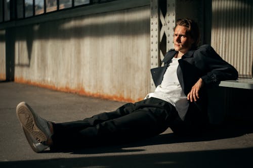 Man in Black Jacket Sitting on Pavement