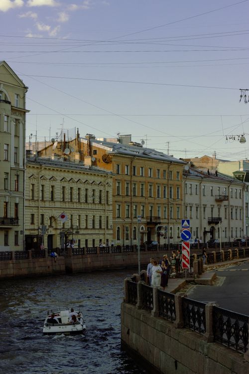 Free Charming urban river scene featuring historical buildings and a small motorboat on a sunny day. Stock Photo