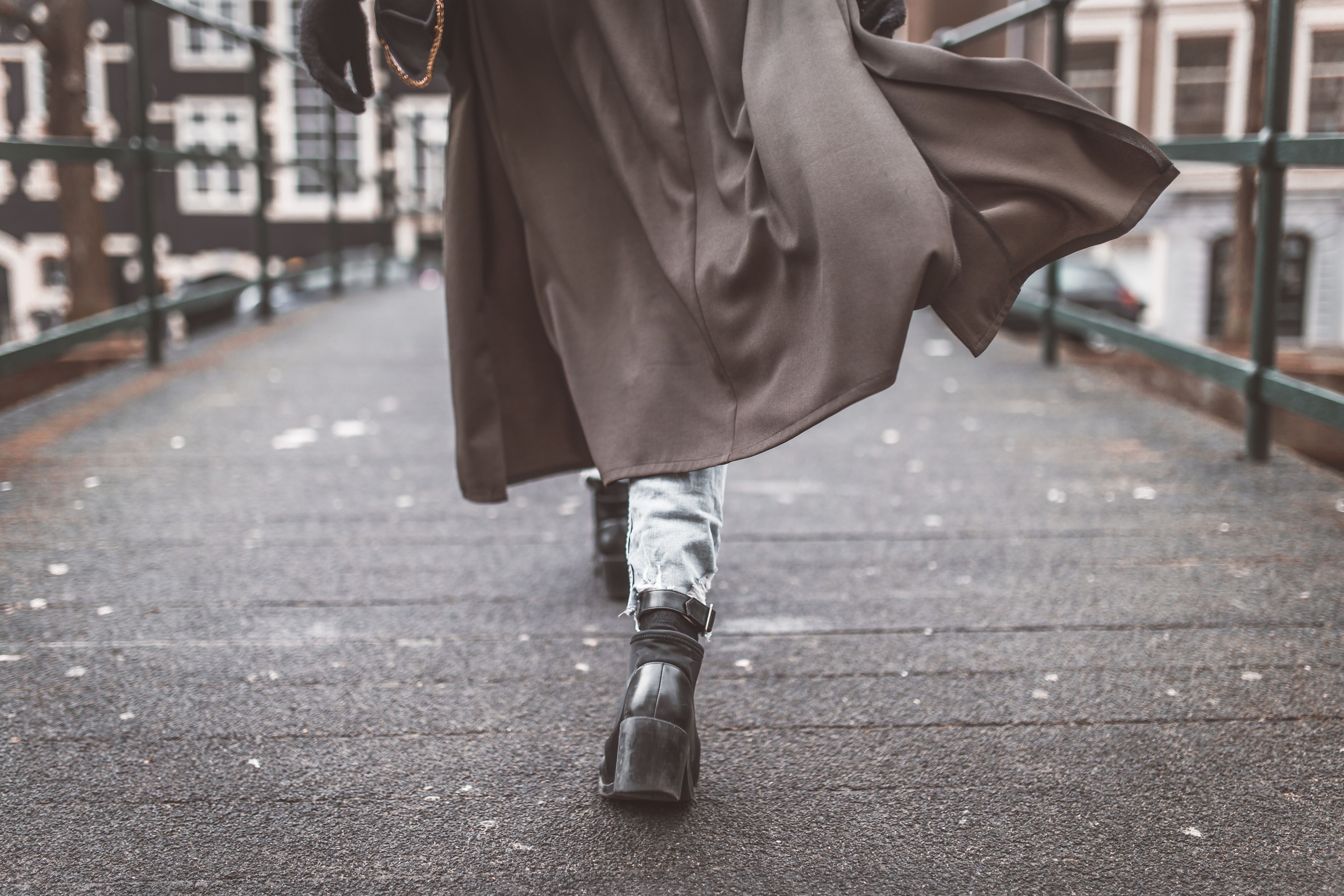 Woman walking in a long coat and boots during autumn in the city