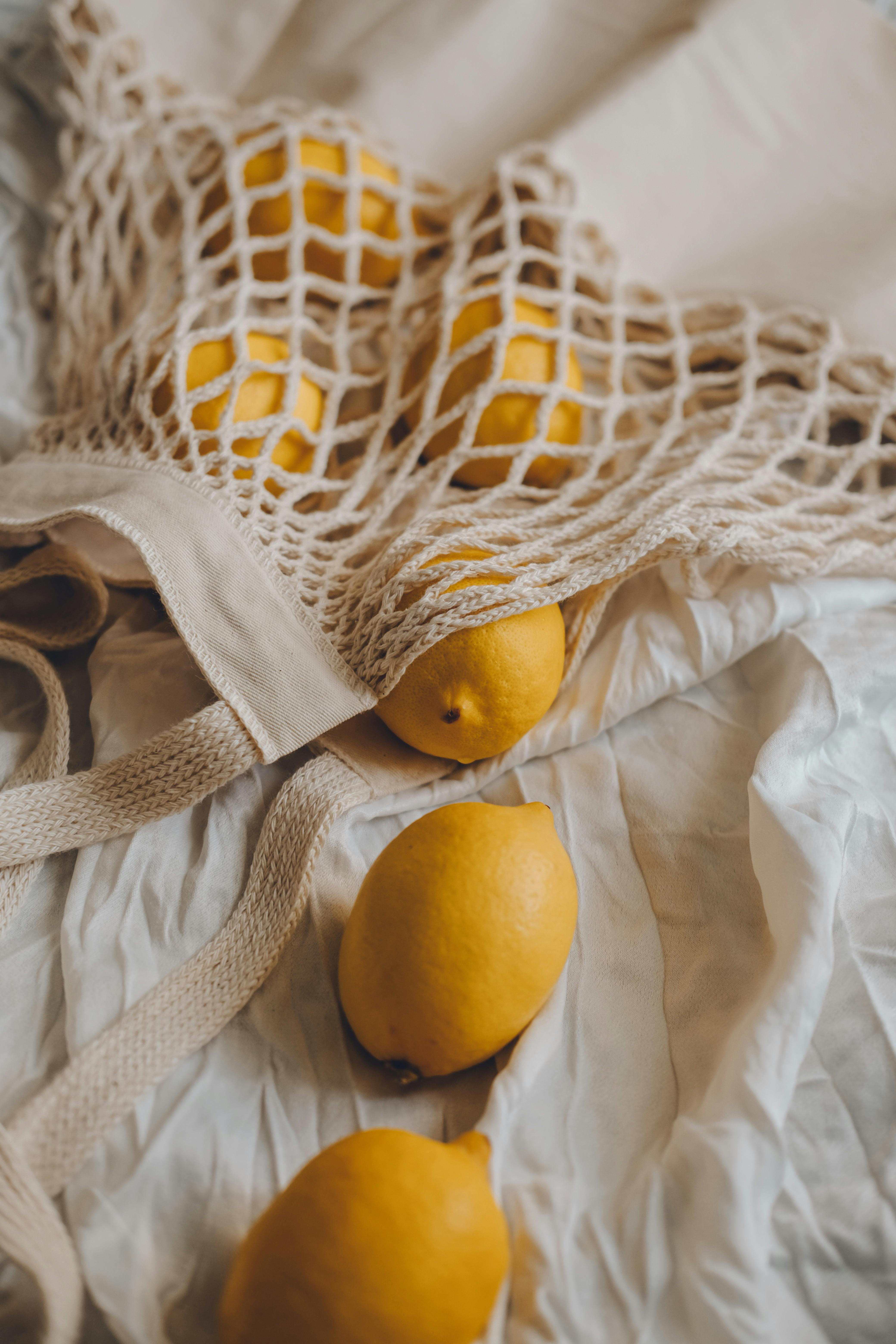 Fresh citrus in mesh bag on beige background. Lemons and limes in