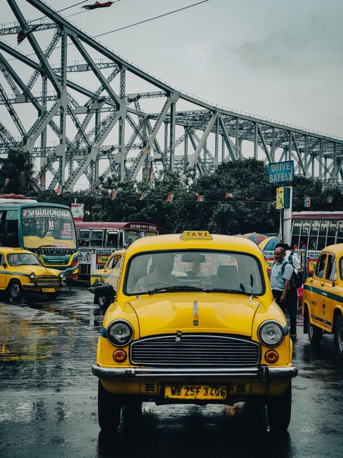 Free Iconic yellow taxi on Howrah Bridge, a rainy day scene in Kolkata, India. Stock Photo