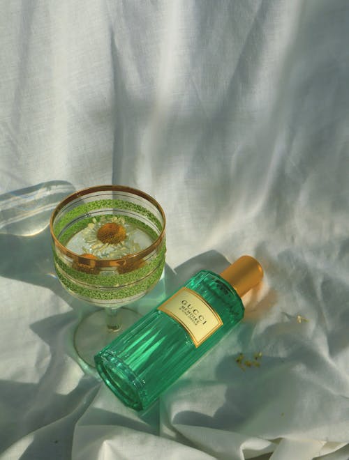 Perfume Vial near Glass with Liquid and Flower