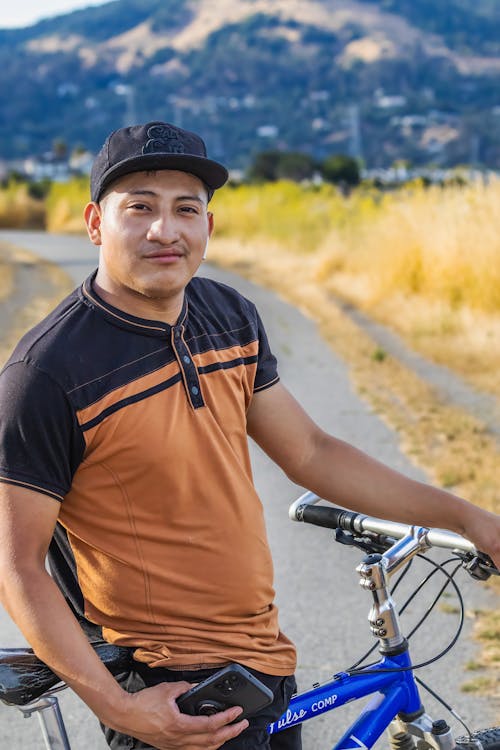 A Man with a Bicycle Standing on a Road 