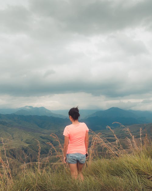 Back View of a Woman Standing on a Mountain Peak and Looking at the View 