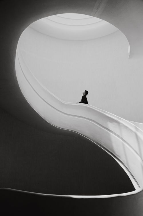 Free Minimalist black and white photograph of a person on a modern spiral staircase. Stock Photo