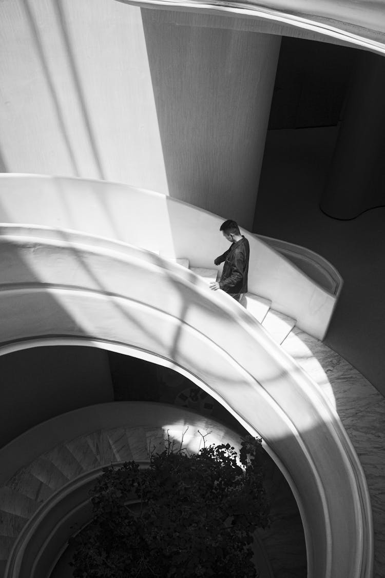 Man Walking Upstairs On Circular Stairs