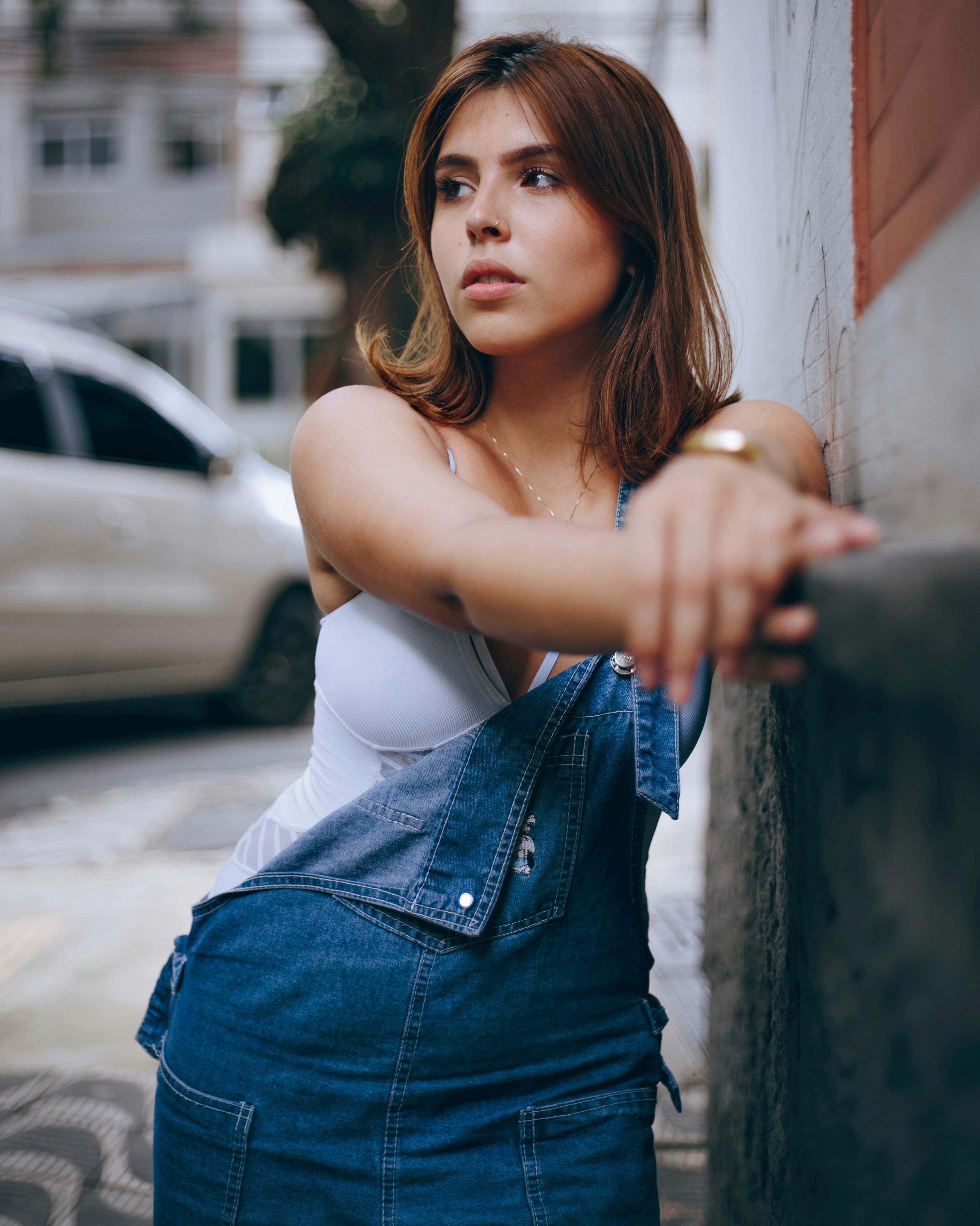 一位穿着牛仔裤的年轻女子站在街上，目光移开