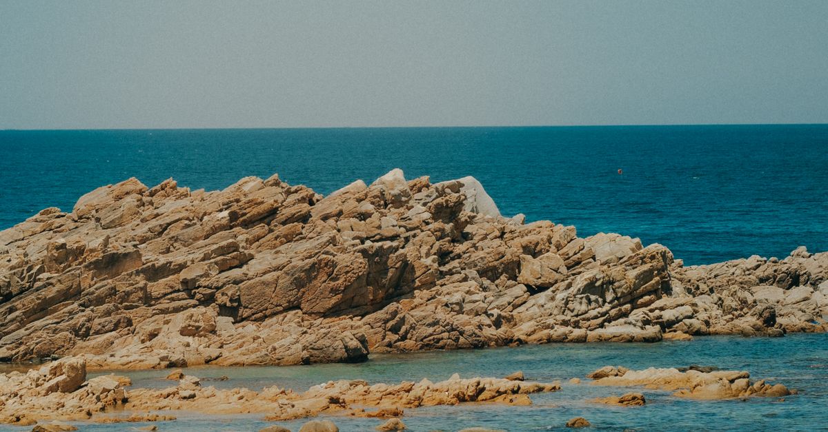 Boats near Rocks on Sea Shore · Free Stock Photo