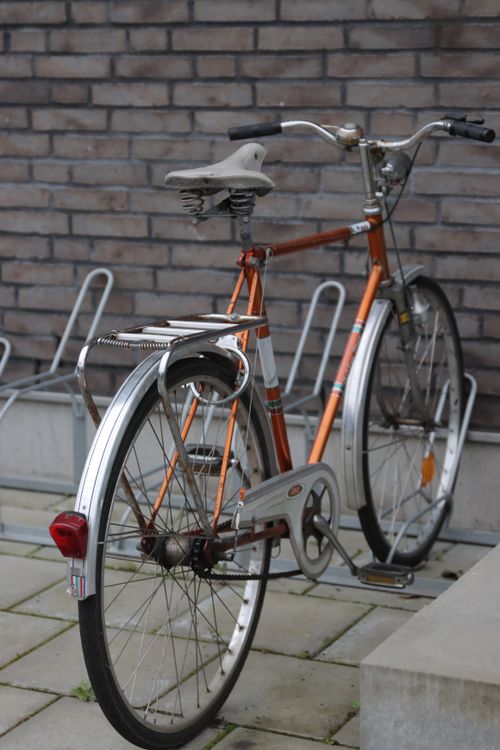 Free A retro-style bicycle parked on a city street against a brick wall, showcasing classic urban charm. Stock Photo