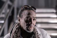 这是一张戴着太阳镜、身着毛皮大衣的男子的特写肖像，展现了时尚与风格