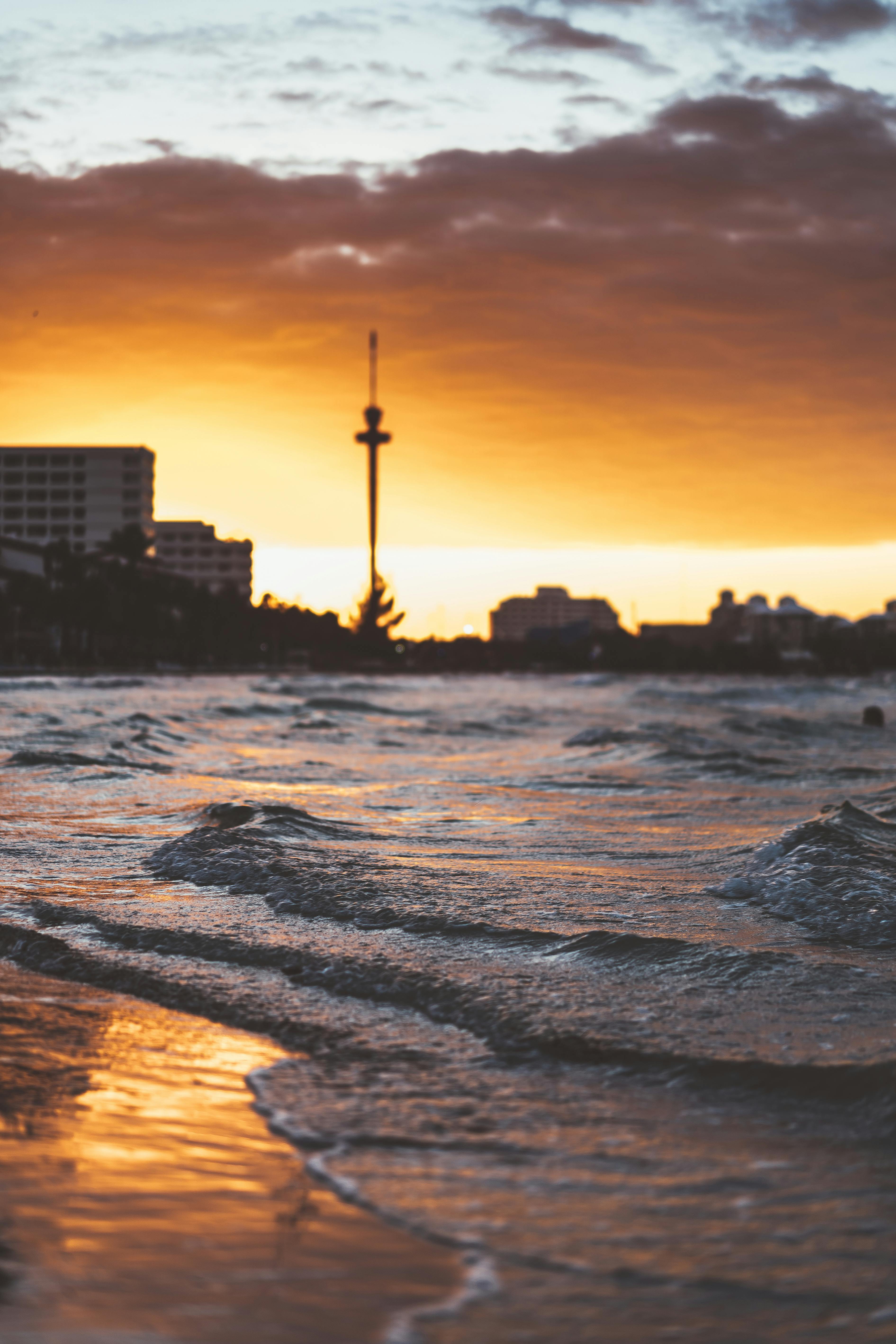 迷人的日落映照在沿海城市的天际线上，海浪轻轻拍打着海岸