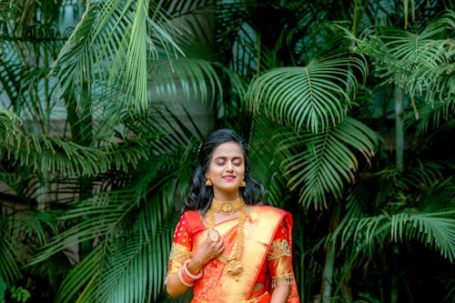 Woman Wearing Orange Sari Among Tropical Leaves 