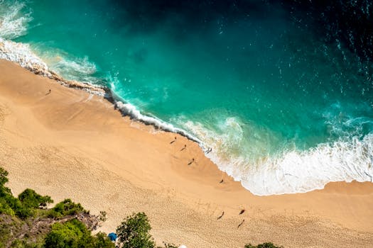 Stunning aerial view of Bali's beach with turquoise waves crashing on golden sand.