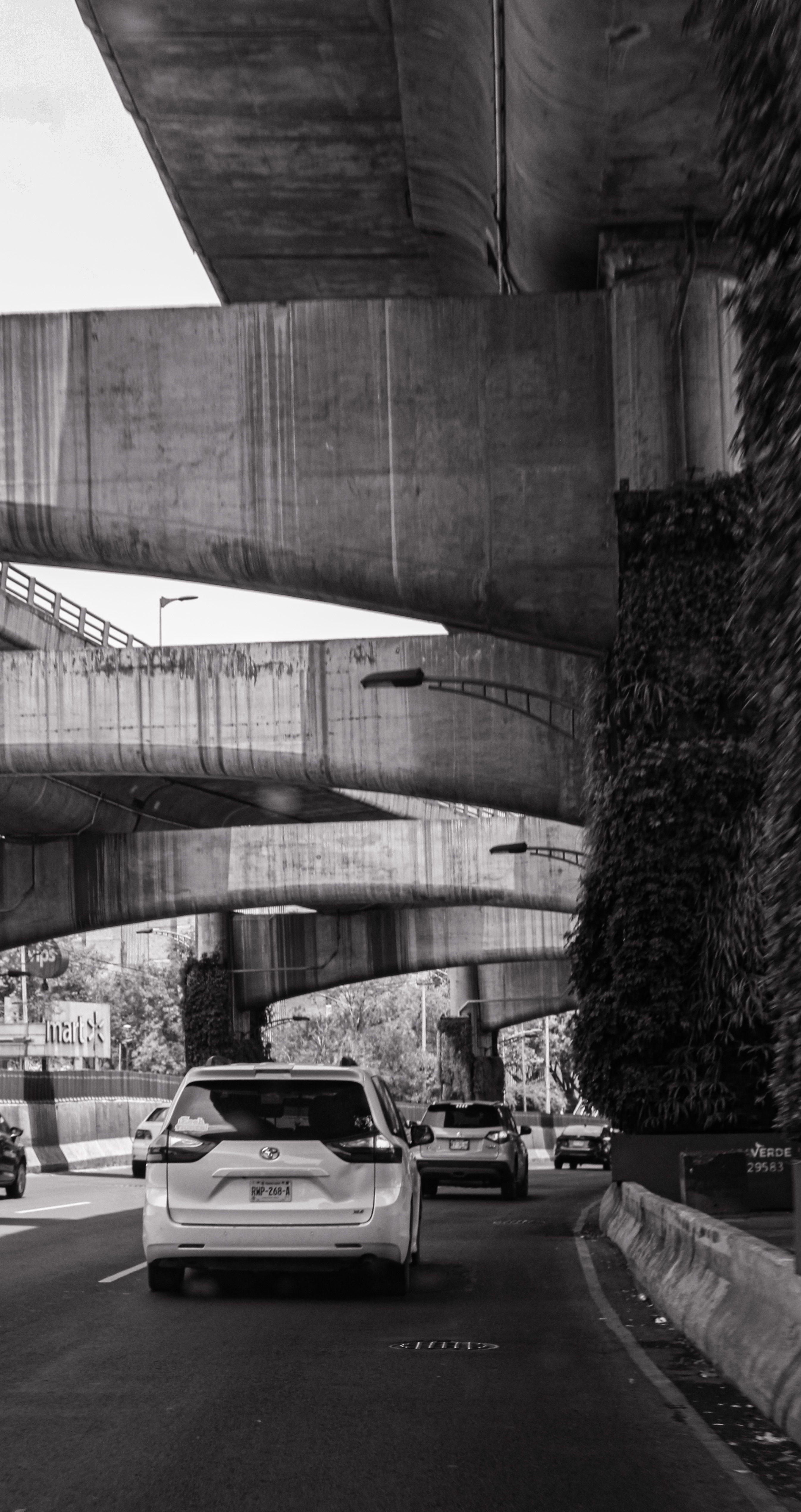 Fotomural Foto estilosa en blanco y negro de varios coches bajo puentes de autopistas en la vibrante Ciudad de México.