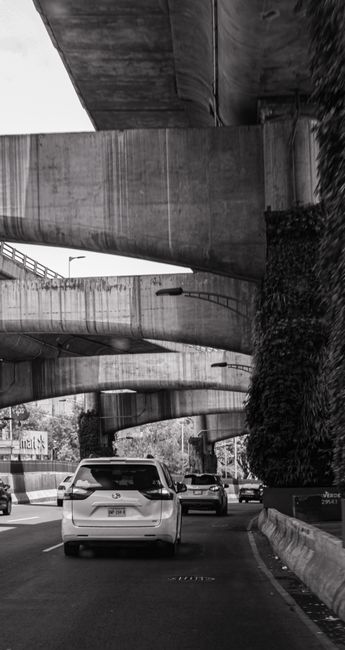 Fotomural Foto estilosa en blanco y negro de varios coches bajo puentes de autopistas en la vibrante Ciudad de México.