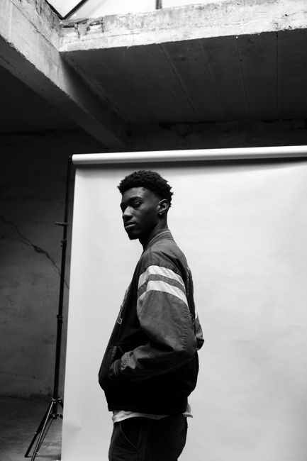 Black and white fashion portrait of a man during a photo session indoors.