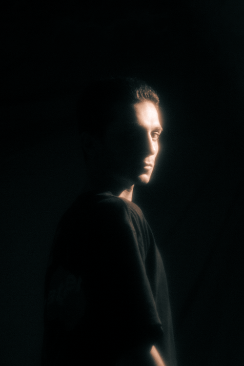 Free Artistic portrait of a man standing in soft dramatic light against a dark background. Stock Photo