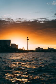 城市天际线上，迷人的日落以海洋为前景，突出了塔楼的轮廓