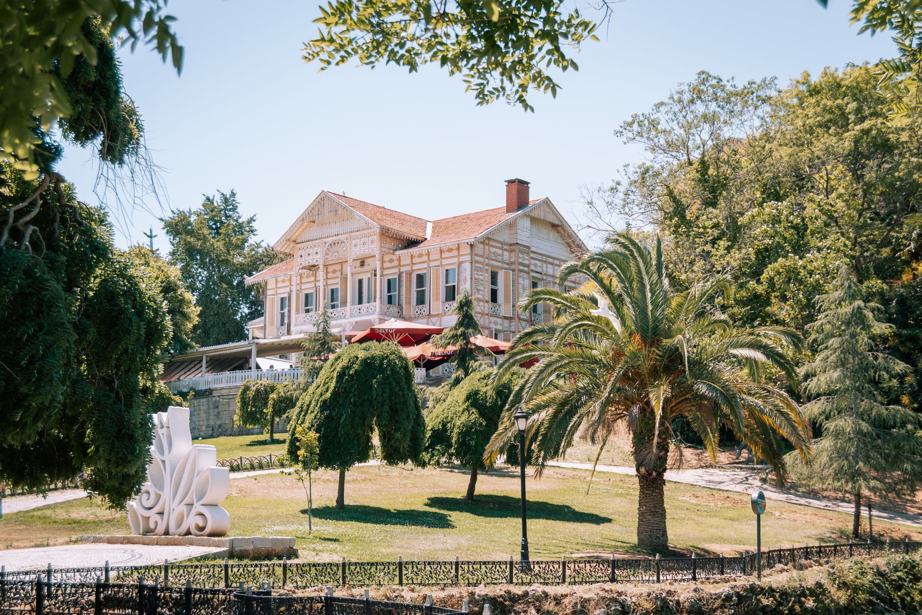 A beautiful villa surrounded by trees and exotic plants in a sunny Istanbul garden.
