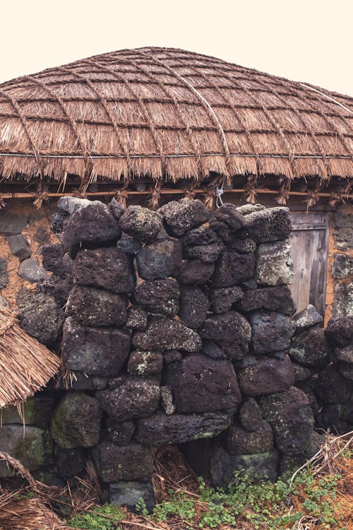 Stone Wall in front of a Village House with a Thatched Roof