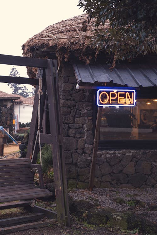 Wooden Swing Bench in front of a Small Bar with a Thatched Roof