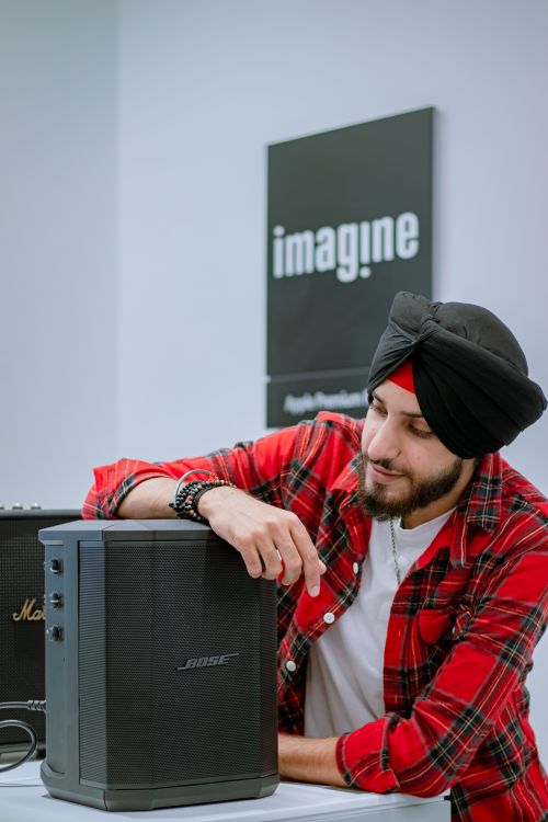 Free South Asian man in plaid shirt examining Bose speaker in electronics shop. Stock Photo