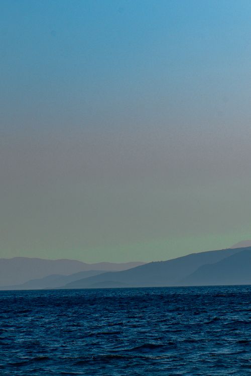 Free A peaceful sea view with distant hills at twilight, capturing serene dusk tones. Stock Photo