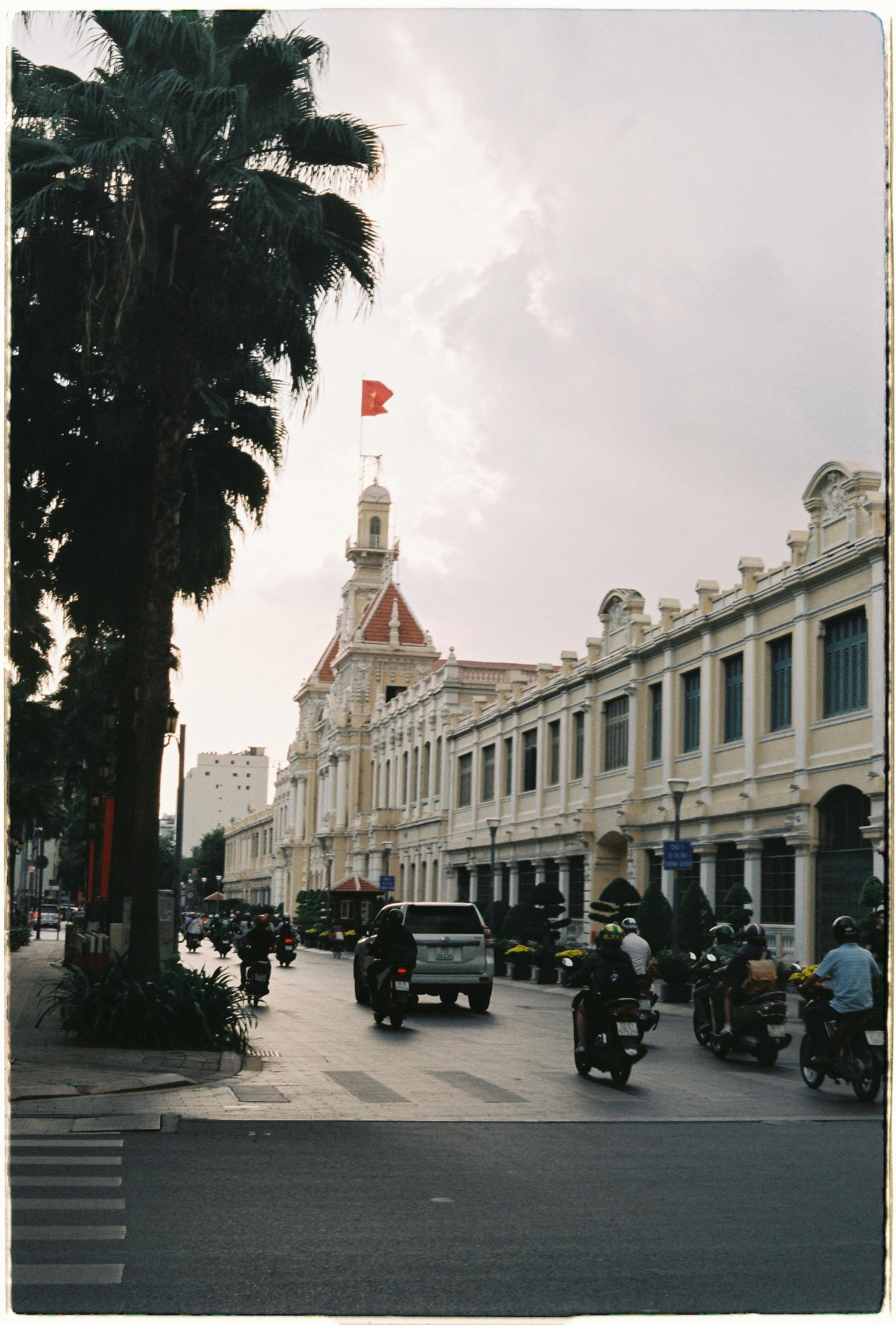 A bustling street scene in Ho Chi Minh City featuring the iconic town hall and vibrant urban life.