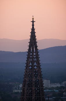 Capture of the iconic Freiburg Minster spire at dusk, with scenic background.