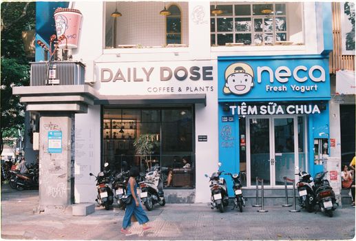 Street view in Vietnam showcasing cafés, shops, and parked scooters