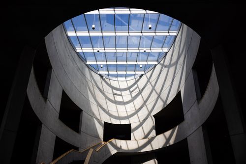 Free Sunlit interior with a minimalistic glass ceiling and concrete walls casting geometric shadows. Stock Photo