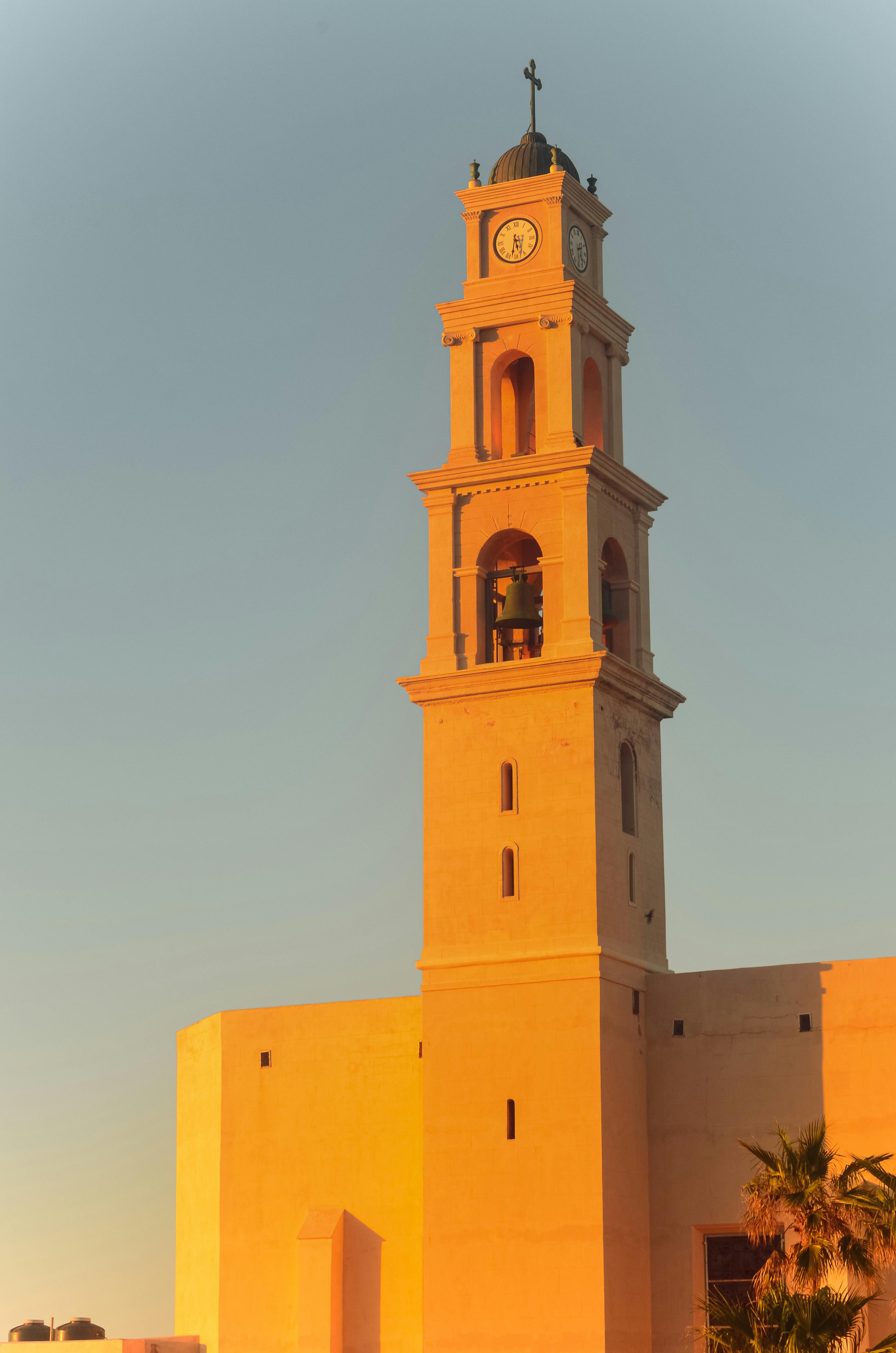 Elegant view of St. Peter's Church clock tower in Jaffa during sunset, showcasing its Ottoman architecture.