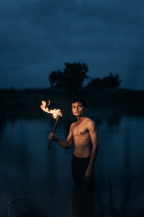 Topless Man Holding Torch in Water