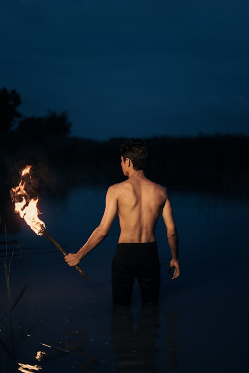 Back View of Man with Torch at Night