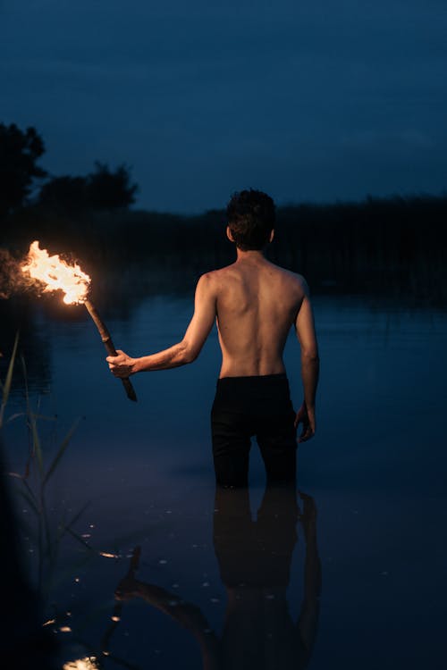 Back View of Man with Torch at Night