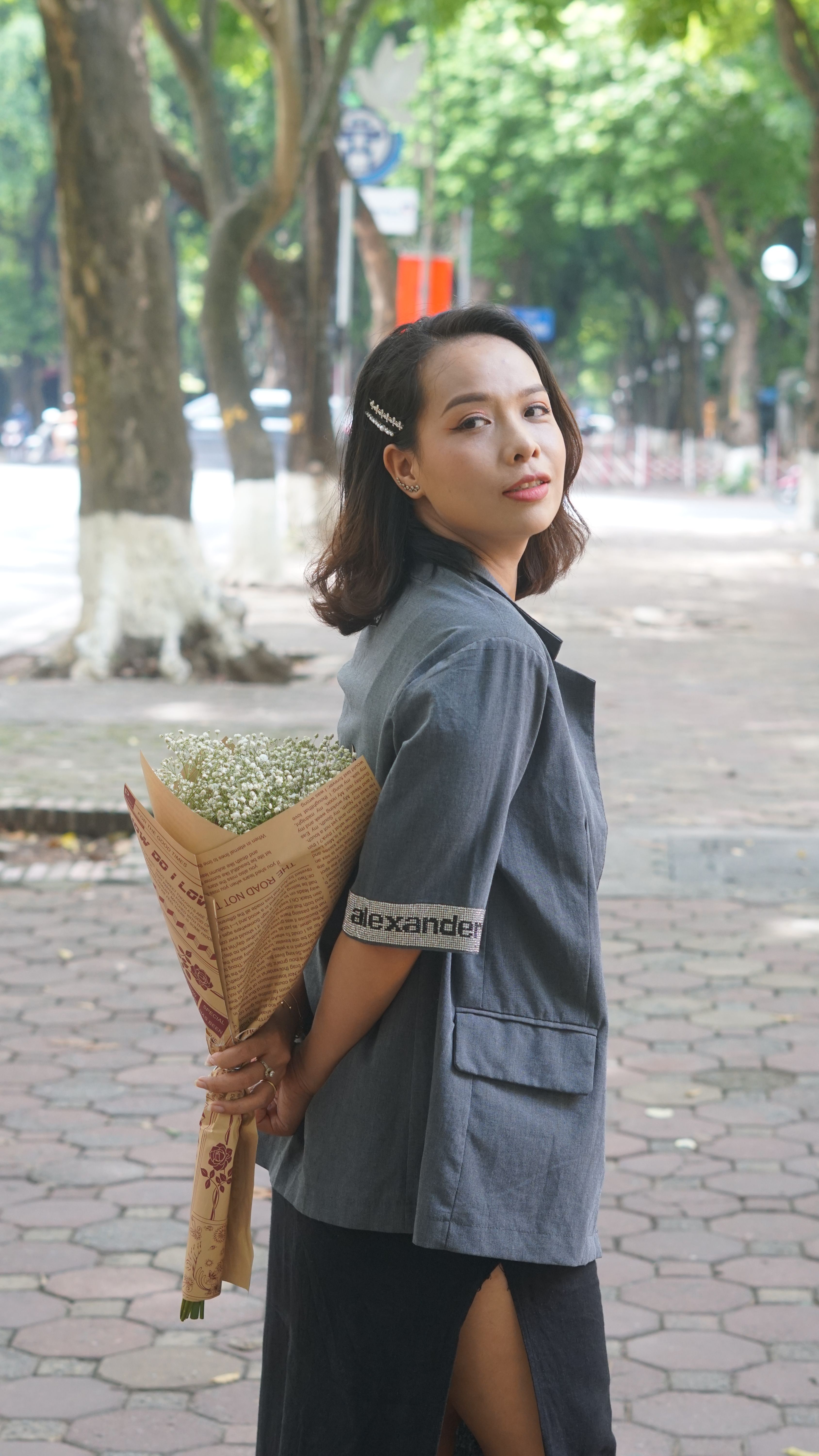 Stylish woman in city street holding a bouquet of flowers, exuding elegance.