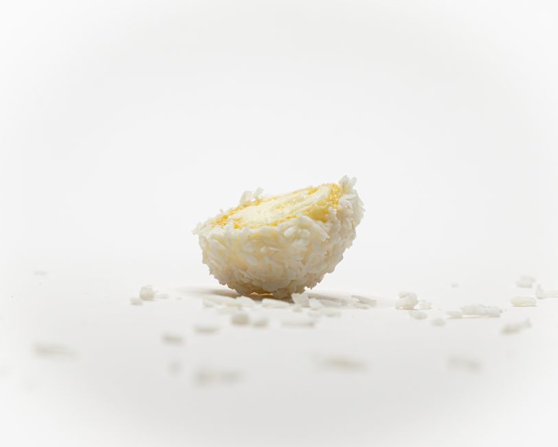Half coconut almond truffle with coconut shreds on a white background, studio shoot.
