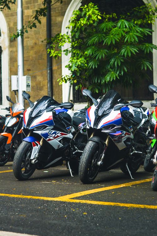 Free A group of sport motorcycles parked in a vibrant city area surrounded by greenery. Stock Photo