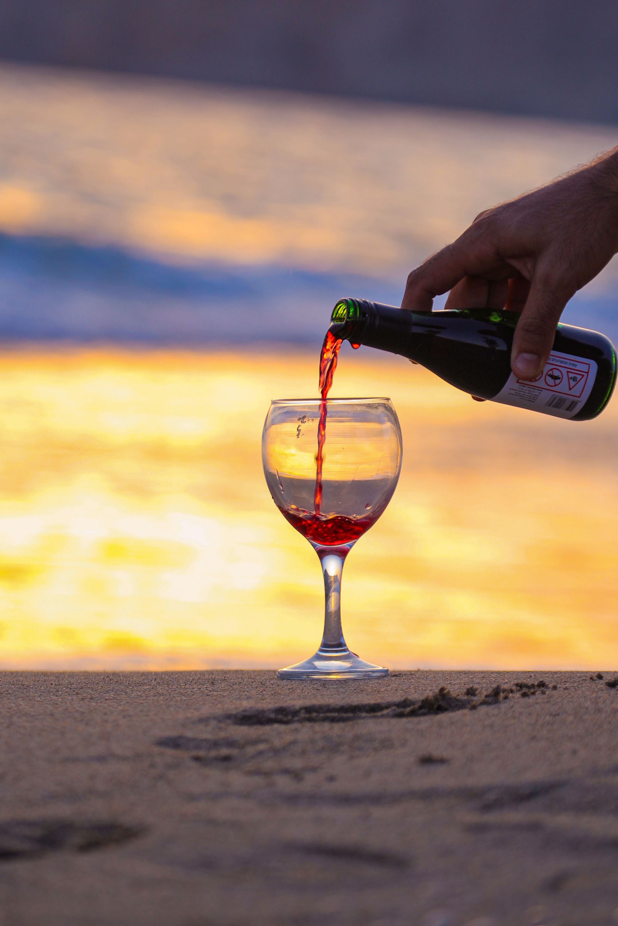 Woman Poring Red Wine to a Glass on a Beach  Free Stock Photo