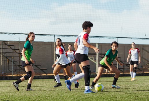 Women soccer players in intense action during a sunny outdoor match, showcasing teamwork and athletic skills.