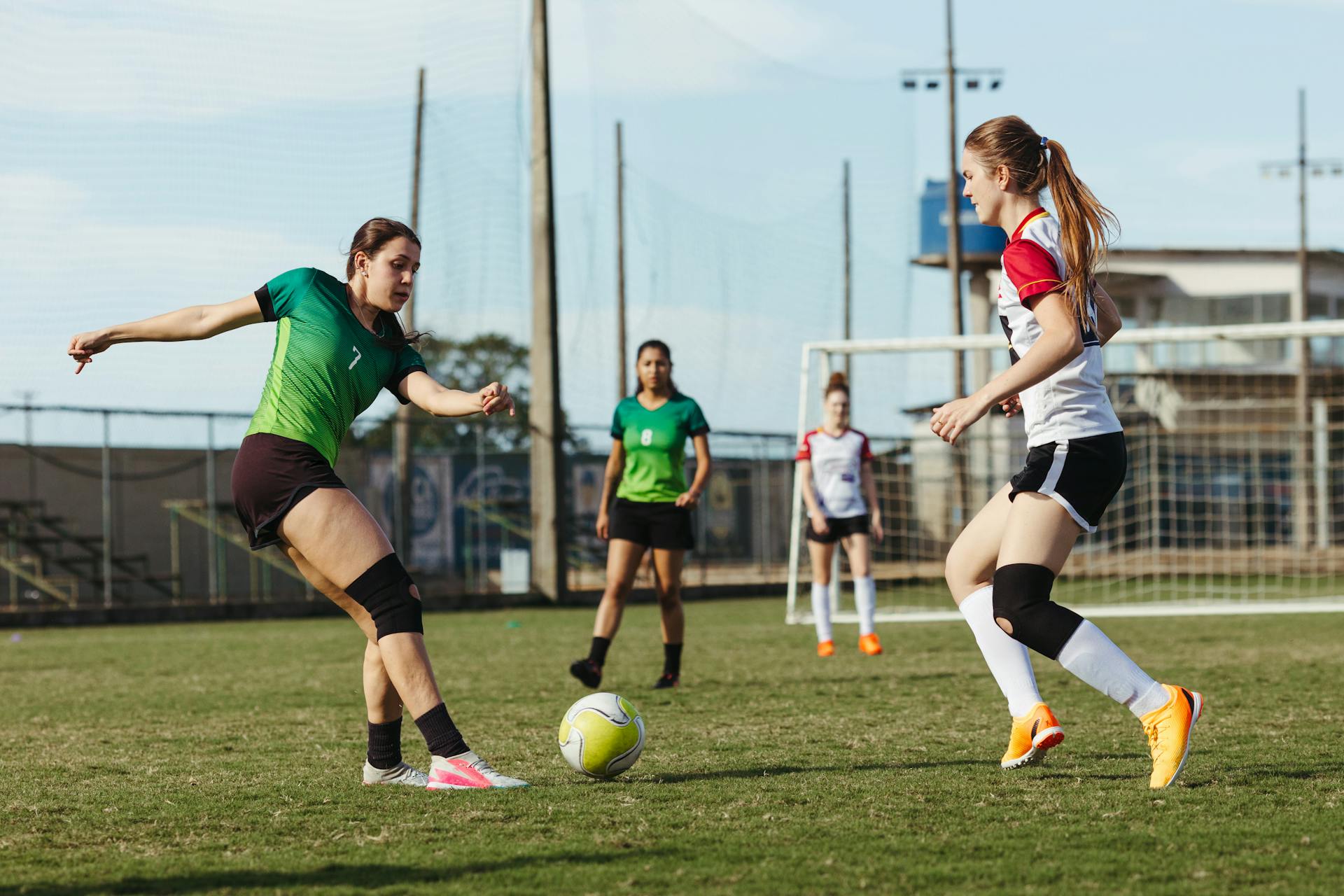 Action-packed scene of women playing a soccer match outdoors with focus on teamwork and competition.