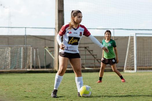 Two teenage girls engaged in a soccer game on an outdoor field, wearing sportswear.